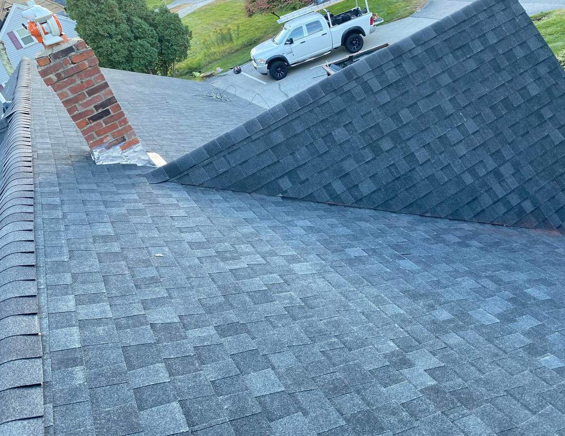Completed asphalt shingle roof with new chimney flashing on a South Shore home
