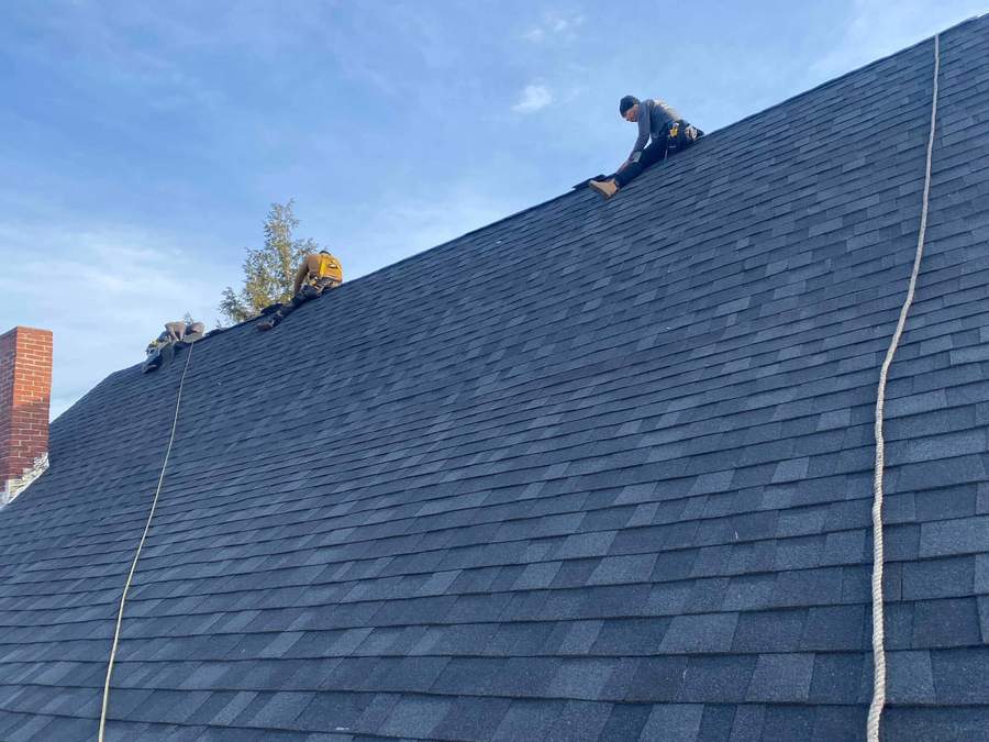 CB Builders Corp. roofing crew installing new asphalt shingles on a steep South Shore roof