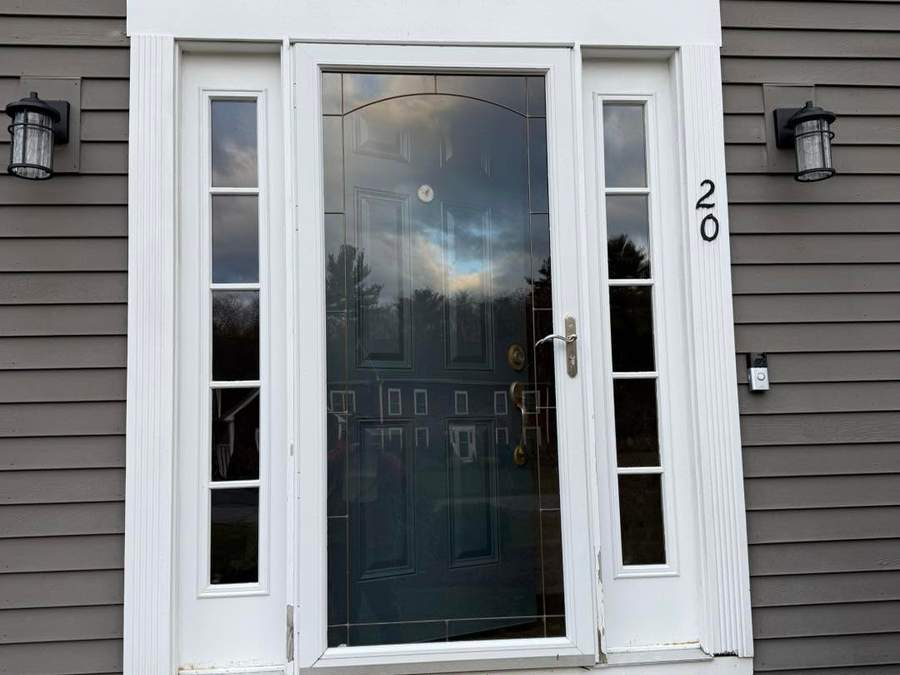 Finished custom Therma-Tru fiberglass entry door with sidelights and new white trim on a gray-sided South Shore home by CB Builders Corp.